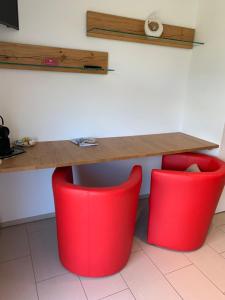 una mesa y dos sillas rojas debajo de una mesa en Ustria / Pensiun Trutg, en Vella