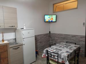 トッレ・ラピッロにあるCasa Vacanza Villa Teresaのキッチン(テーブル付)、壁掛けテレビが備わります。