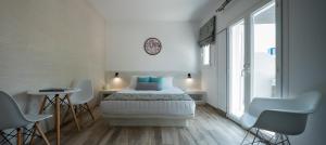 - une chambre blanche avec un lit, une table et des chaises dans l'établissement Oasis Hotel, à Fira