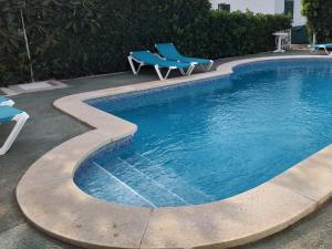 una piscina con 2 sillas azules al lado en Apartamentos Delfines, en Cala Blanca