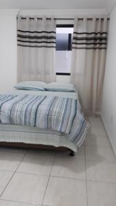 Schlafzimmer mit einem Bett mit Vorhängen und einem Fenster in der Unterkunft Marcella's Holiday House - 100 mts Praia do Morro in Guarapari