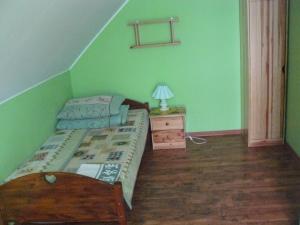 a green bedroom with a bed and a night stand at Łosiowy Kąt in Goniadz
