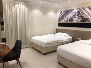 a bedroom with two beds and a desk and a chair at Dar Al Maamon Furnished Apartment in Jeddah +19 photos