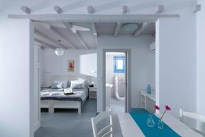 a white bedroom with a bed and a table at Evgenia Residences in Agios Ioannis Kaspaka