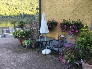 un patio con tavolo, ombrellone e fiori di Villa Marilena con accesso diretto al lago a Ranzanico