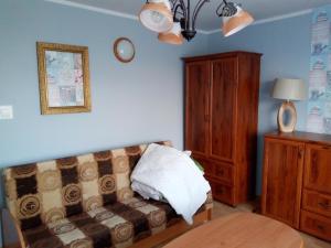 ein Wohnzimmer mit einem Sofa und einem Holzschrank in der Unterkunft Cichy Zakątek Junoszyno in Junoszyno