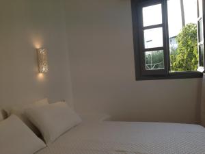 a white bedroom with a bed and a window at Maistrali Studios & Apartments in Plaka