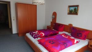 - une chambre avec 2 lits dotés d'oreillers rouges et violets dans l'établissement Kaufhaus Feldberg, à Rinken