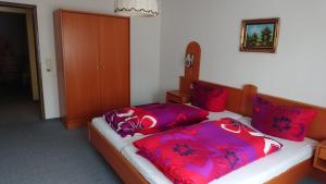 1 Schlafzimmer mit 2 Betten mit roten und violetten Kissen in der Unterkunft Kaufhaus Feldberg in Rinken