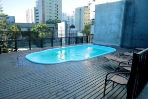 ein großer blauer Pool auf einer Terrasse mit Stühlen und Gebäuden in der Unterkunft Belíssimo Apart Com Vista Mar in Fortaleza