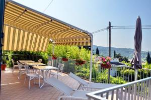 a patio with tables and chairs and an umbrella at B&B IL RICCIO in Costermano
