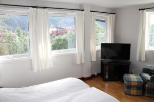 a bedroom with a bed and a tv and windows at Kløver Hotel in Sauda