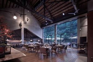 uma sala de jantar com mesas e cadeiras e janelas grandes em Yangshuo Sugar House em Yangshuo