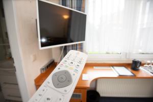 a remote control in front of a desk with a television at Gästehaus Am Vogelsang in Kerpen