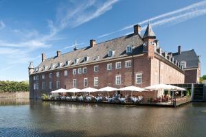 a large building with tables and umbrellas in front of it at Romantik Parkhotel Wasserburg Anholt in Isselburg