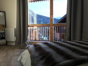 a bedroom with a large window with a mountain view at VAUJANYLOCATIONS - La Fare Apt 12 in Vaujany