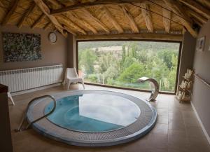 einen Whirlpool in einem Zimmer mit einem großen Fenster in der Unterkunft Apartamentos Rurales de la Sexma del Sabinar in Corduente