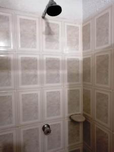 Baño de azulejos blancos con ducha y techo en Hotel Marli Plaza, en Mocoa