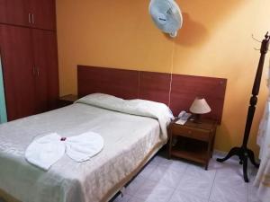 Hotel Marli Plaza في Mocoa: غرفة نوم بسرير مع مروحة وموقف ليلي