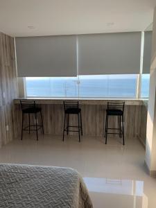 Un dormitorio con sillas y un bar con vistas al océano. en Studio Atlântica II, en Río de Janeiro