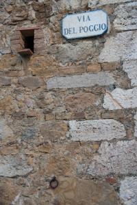 uma parede de pedra com uma placa de rua em VINO SUITE em San Quirico dʼOrcia