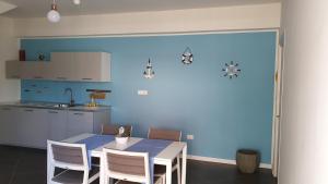 uma cozinha com uma mesa e cadeiras e uma parede azul em Marina bay house em Rossano