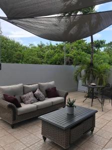 a couch sitting on a patio under an umbrella at Palmeras Del Mar in Isabela