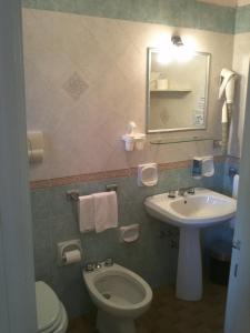 ein Badezimmer mit einem Waschbecken, einem WC und einem Spiegel in der Unterkunft Hotel Abbaruja in Olbia