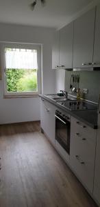 a kitchen with white cabinets and a sink and a window at Moi Tied in Norddeich +13 photos