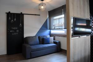 a living room with a blue couch and a tv at Q Luxury Rooms in Thessaloniki