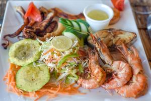 a plate of food with shrimp and vegetables and dipping sauce at Ifa Beach Resort in Jambiani