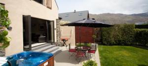 een terras met een tafel, stoelen en een parasol bij Charming Wanaka Cottage in Wanaka +5 foto's