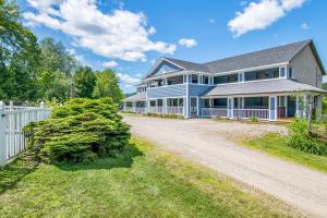 a large house with a white fence and a driveway at Grey Fox Inn in Stowe