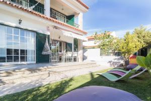 a house with a yard with lawn chairs at Magnólia Beach House - Cascais in Cascais