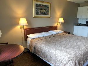 um quarto de hotel com uma cama e uma mesa em Travellers Inn em Calgary