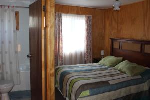 1 dormitorio con cama, ducha y ventana en Hostal Internacional, en Valdivia