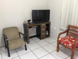 a living room with a television and a chair at Apto Floramar in Belo Horizonte