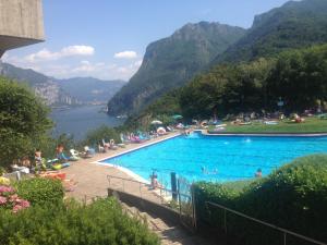 a large swimming pool with people sitting around it with mountains at Bellagio Dream in Valbrona