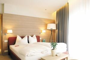 a hotel room with a bed with white sheets and pillows at Falkensteiner Residences edelweiss in Katschberghöhe