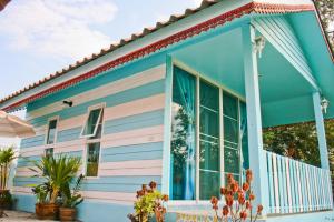 a blue and pink house with plants in front of it at Boathouse Resort Suanphung in Suan Phung