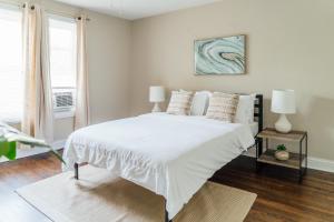 a white bedroom with a large bed and a window at Spacious 2BR Apartment near Airport - Central Charming in Dunning