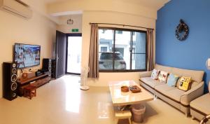 uma sala de estar com um sofá e uma televisão em Fun Place to Stay B&B em Weiqian