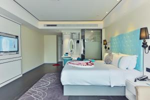 um quarto com uma grande cama branca e uma televisão em Xana Hotelle Shenzhen Airport Terminal em Shenzhen