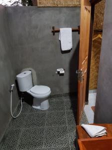 ein Bad mit WC und Handtüchern an der Wand in der Unterkunft Taman Menjangan homestay by SnorkelingMenjangan in Banyuwedang