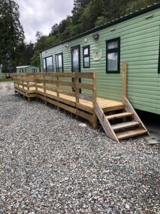 une rampe en bois menant à une maison verte dans l'établissement 62 Glenfinart Caravan Park, à Dunoon