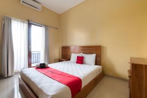 1 dormitorio con 1 cama grande con manta roja en RedDoorz @ Kerta Dalem Sidakarya, en Denpasar