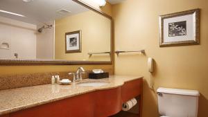 a bathroom with a toilet, sink, and mirror at Best Western Plus Waterville Grand Hotel in Waterville