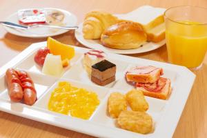 een bord met diverse zoete deegwaren en een glas sinaasappelsap bij Hotel Vista Kanazawa in Kanazawa