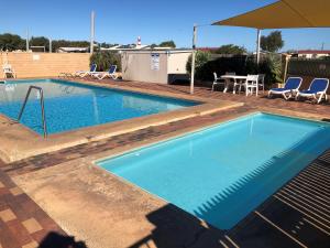 a large swimming pool with a table and chairs at Belair Gardens Caravan Park in Geraldton
