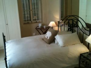 a bed with white sheets and pillows in a bedroom at Cheviot Place Guest House in Cape Town